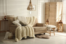 Cozy living room interior with beige sofa, knitted blanket and cushions